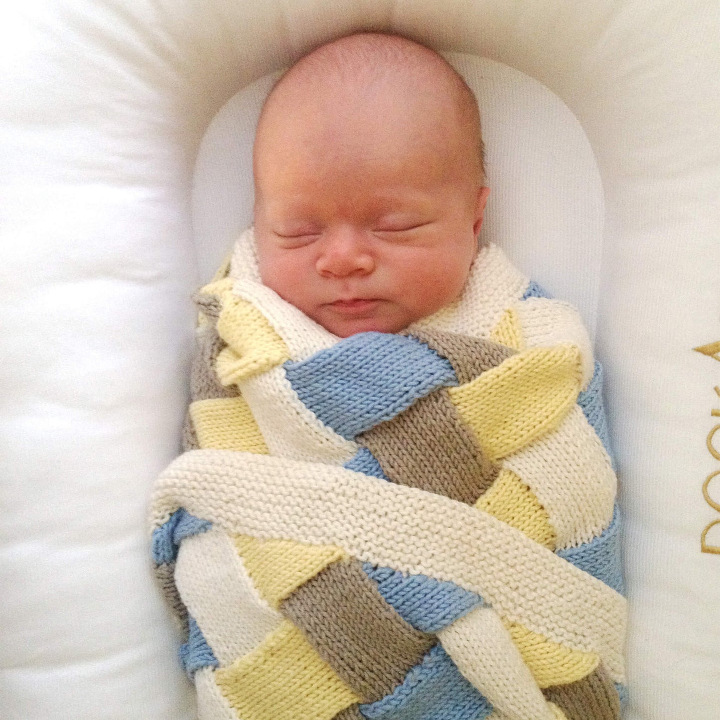 sleeping baby modelling a basketweave baby blanket knit pattern