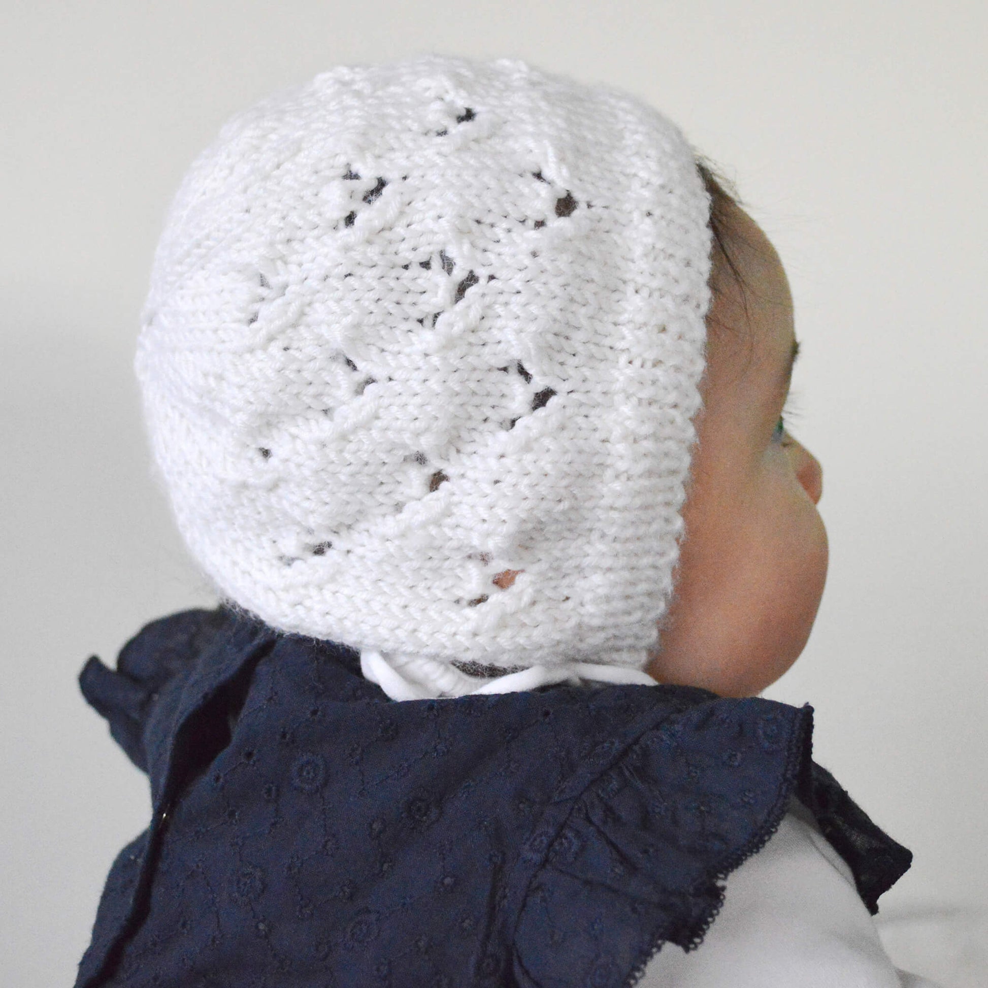 baby sitting to model a baby bonnet knitting pattern