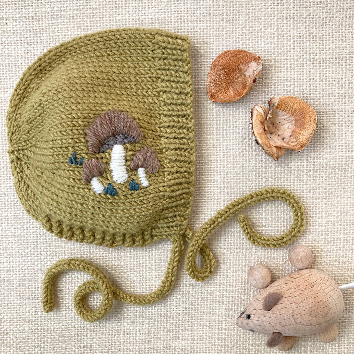 a baby bonnet knitting pattern with embroidered toadstools detail