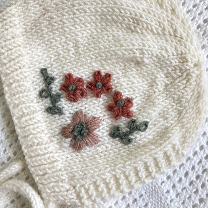 close up of yarn embroidery on baby bonnet knitting pattern