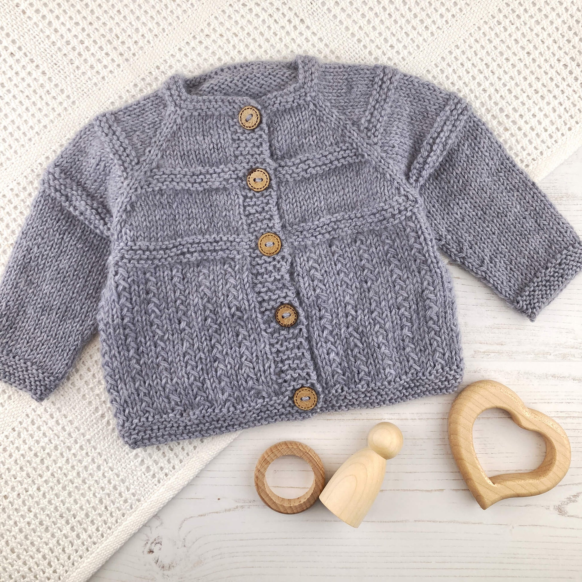 a baby cardigan knitting pattern shown knitted in mid grey yarn