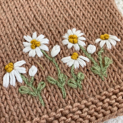 a close up photo of the daisy embroidery on knitted baby cardigan