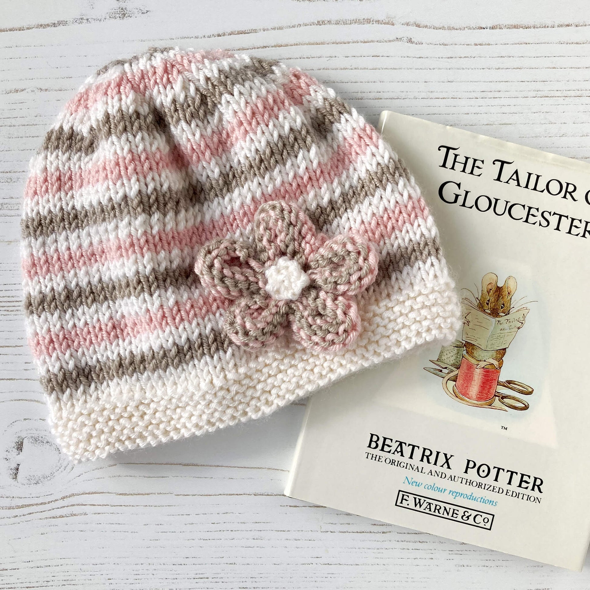 a baby hat with flower knitting pattern . hat is styled adjacent to a story book