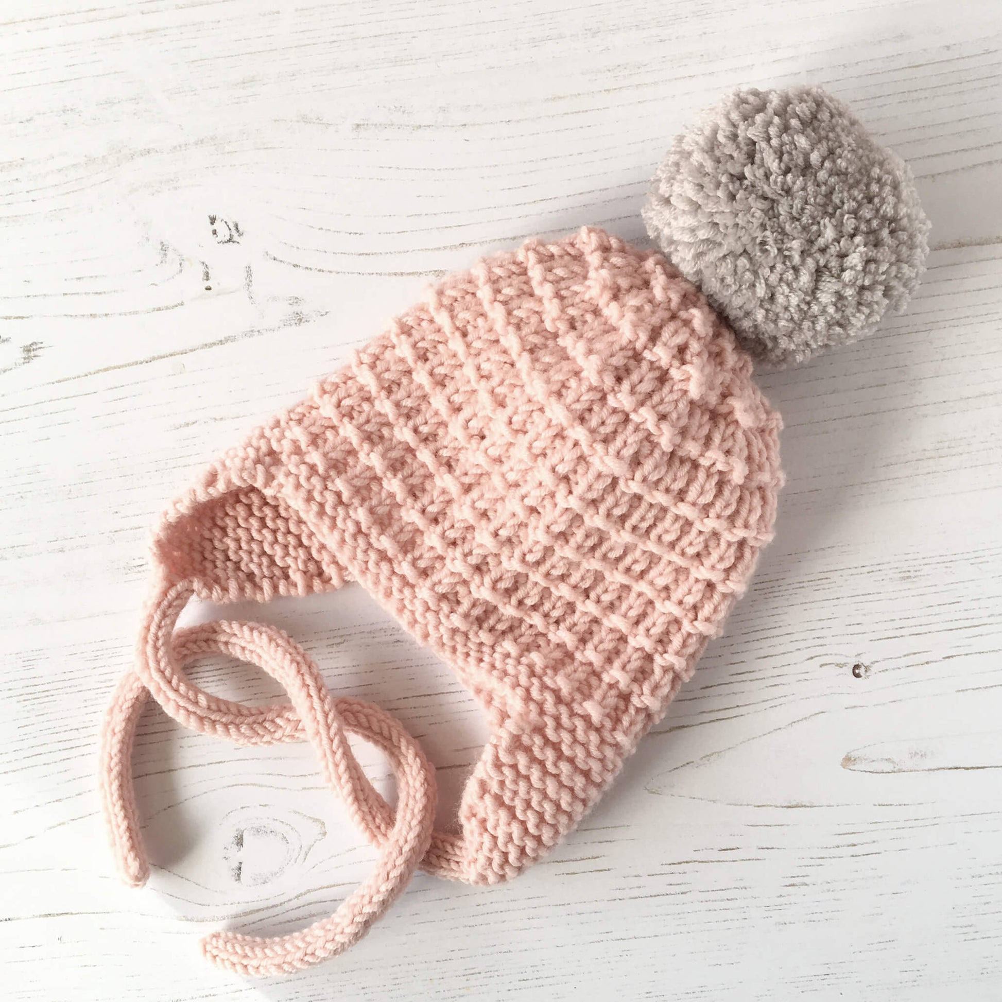 a baby hat pattern that is easy to knit. sample shown in pale pink with grey pompom