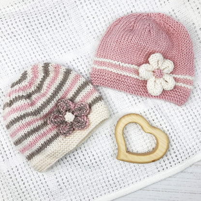 a baby hat pattern for beginner knitters. two hats are shown, one in pink with white flower, the second with taupe and pink stripes