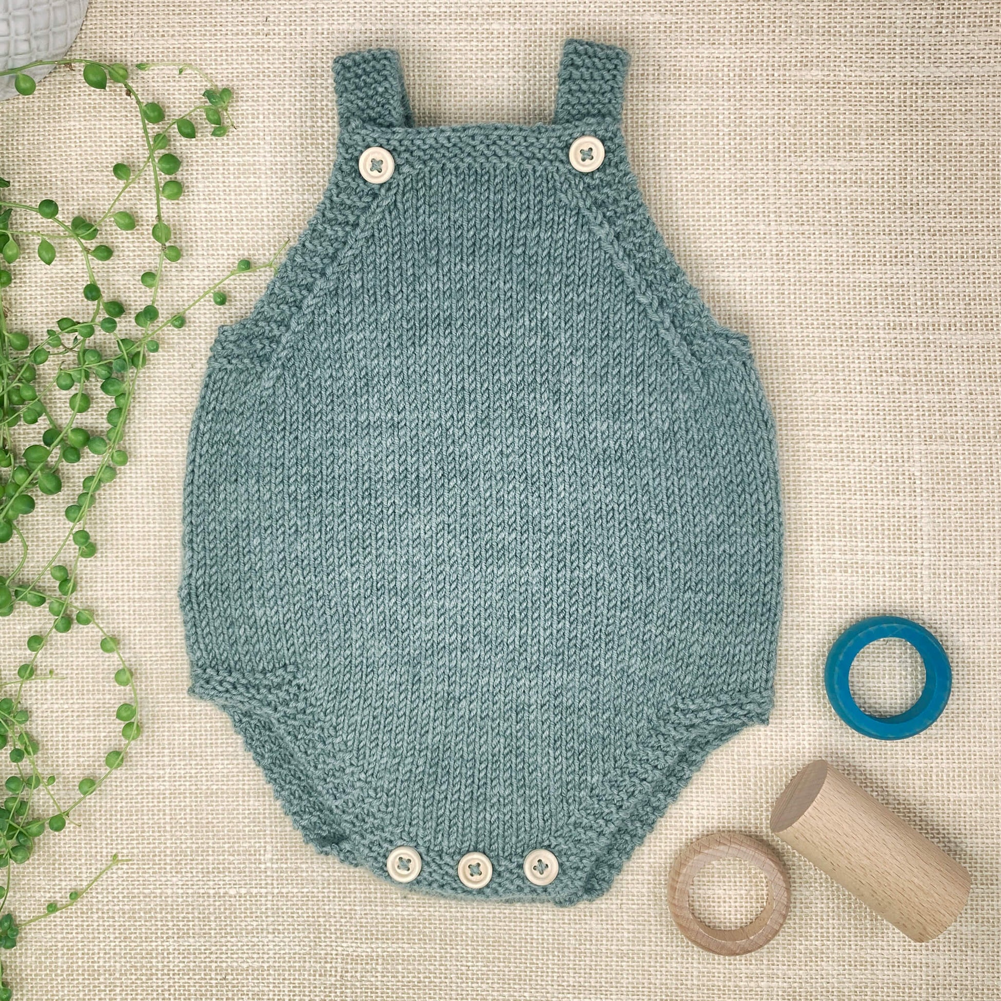 a beginner knitting pattern for a baby romper. the sample shown is blue