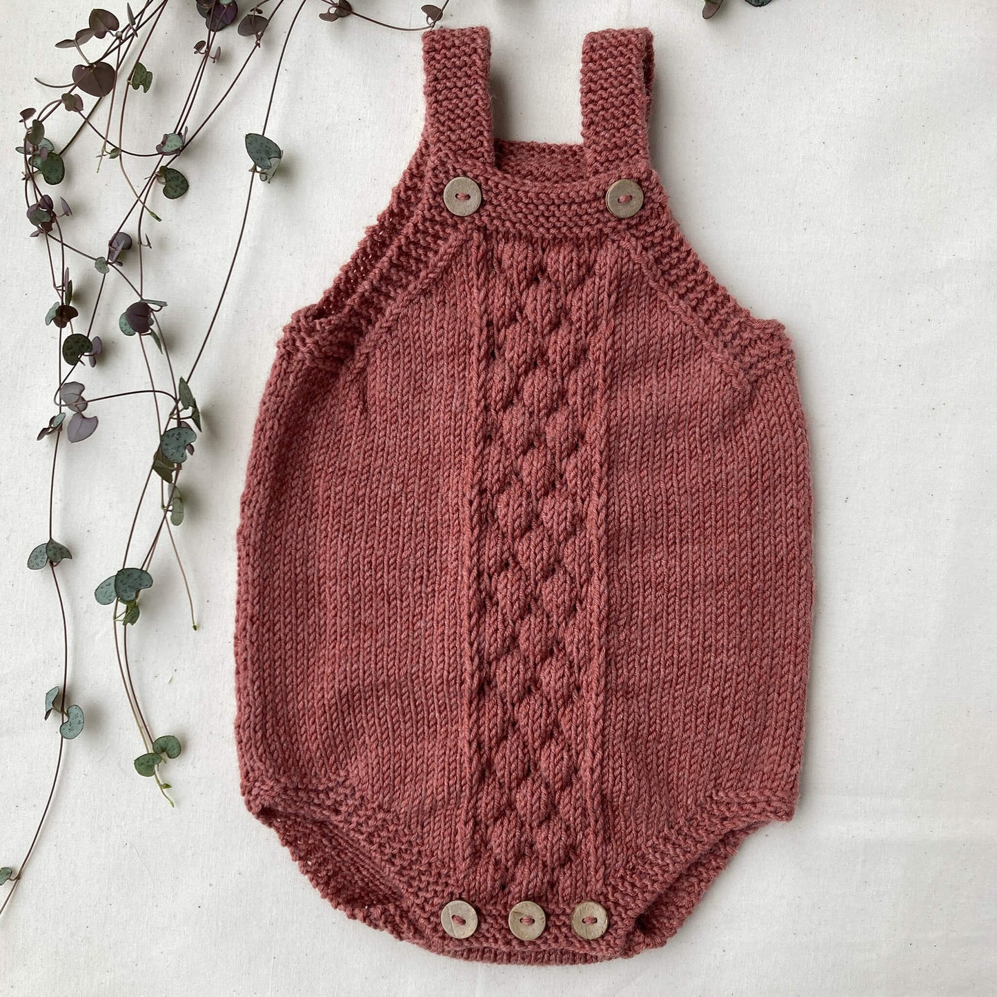 baby romper knit pattern sample shown in rust colour yarn