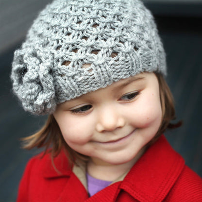 a beanie hat knitting pattern with a flower modelled by a little girl