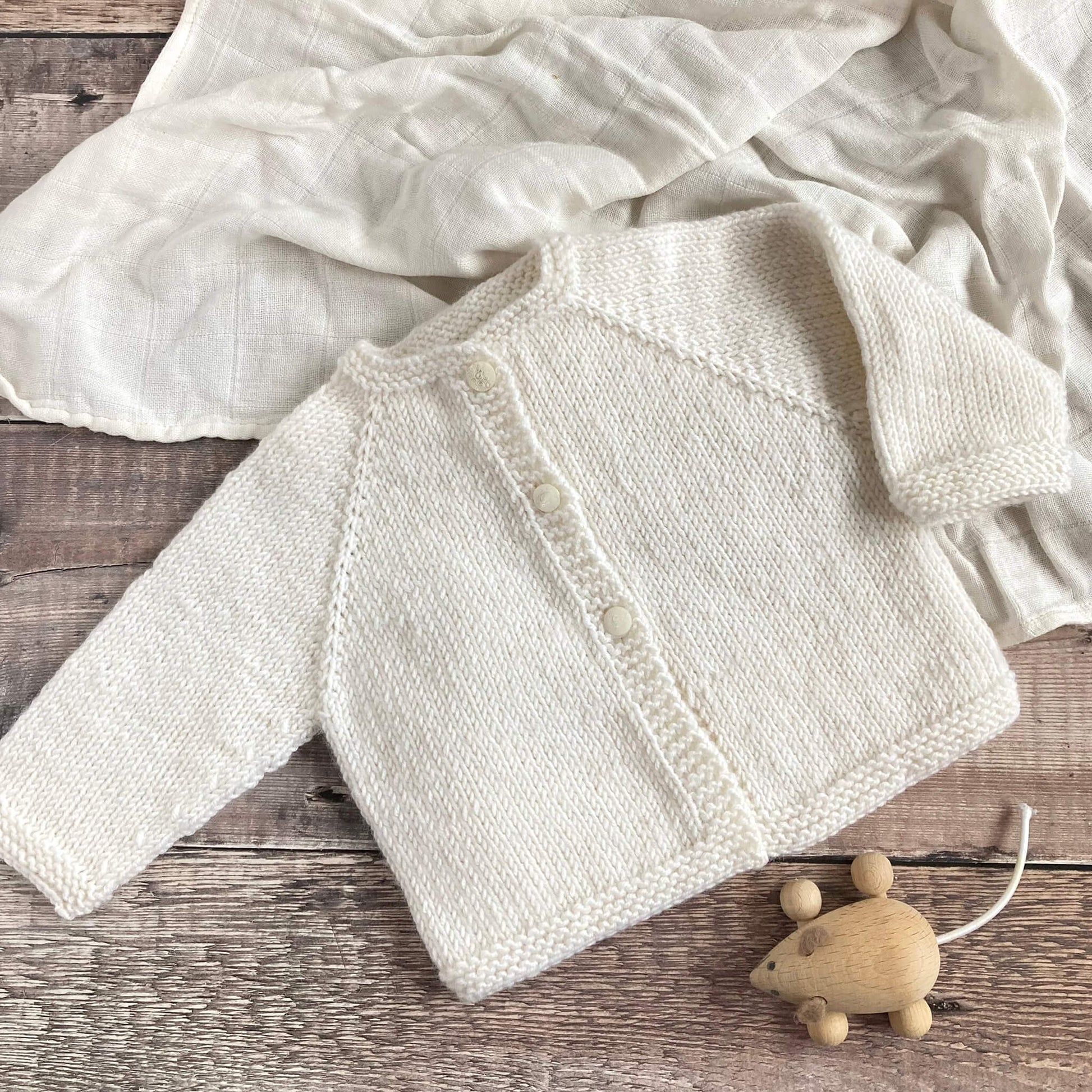 sample for a beginner baby cardigan knitting pattern knitted in white yarn 