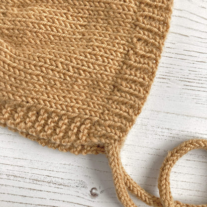 close up of knitting stitches in beginner knitting pattern for a baby bonnet