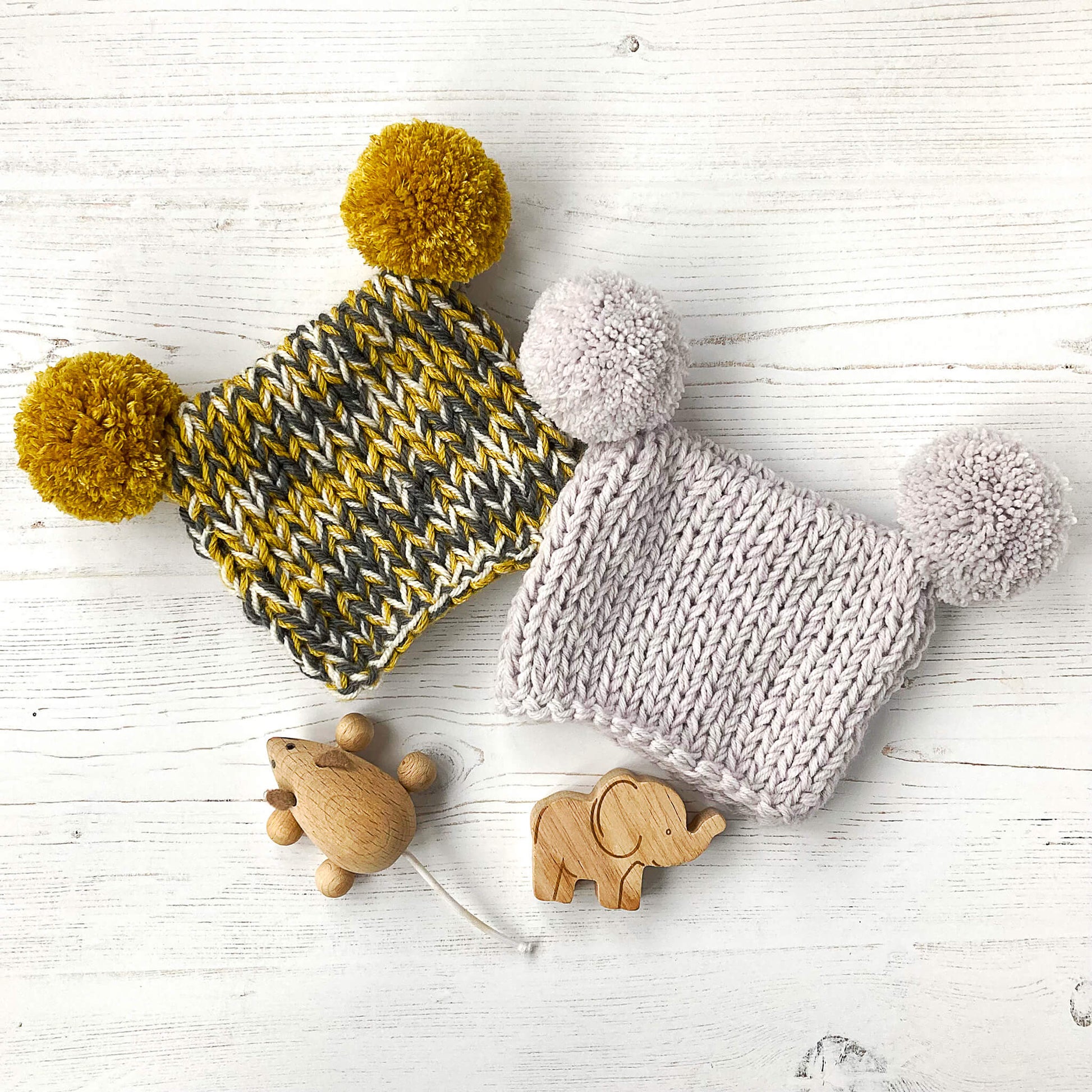 a beginner level knitting pattern for a baby hat with pompoms