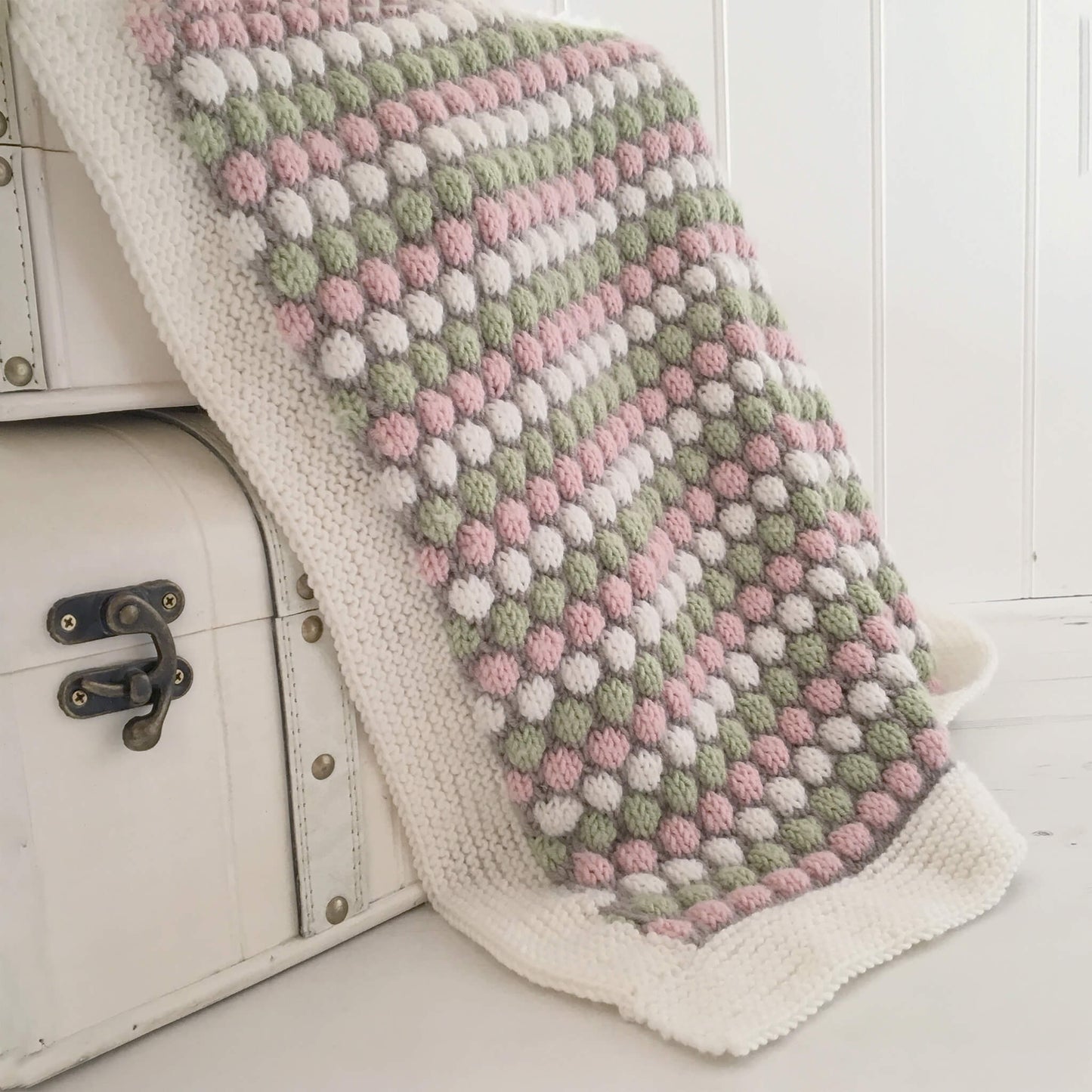 a blanket knit pattern. sample is draped over stacked toy chests