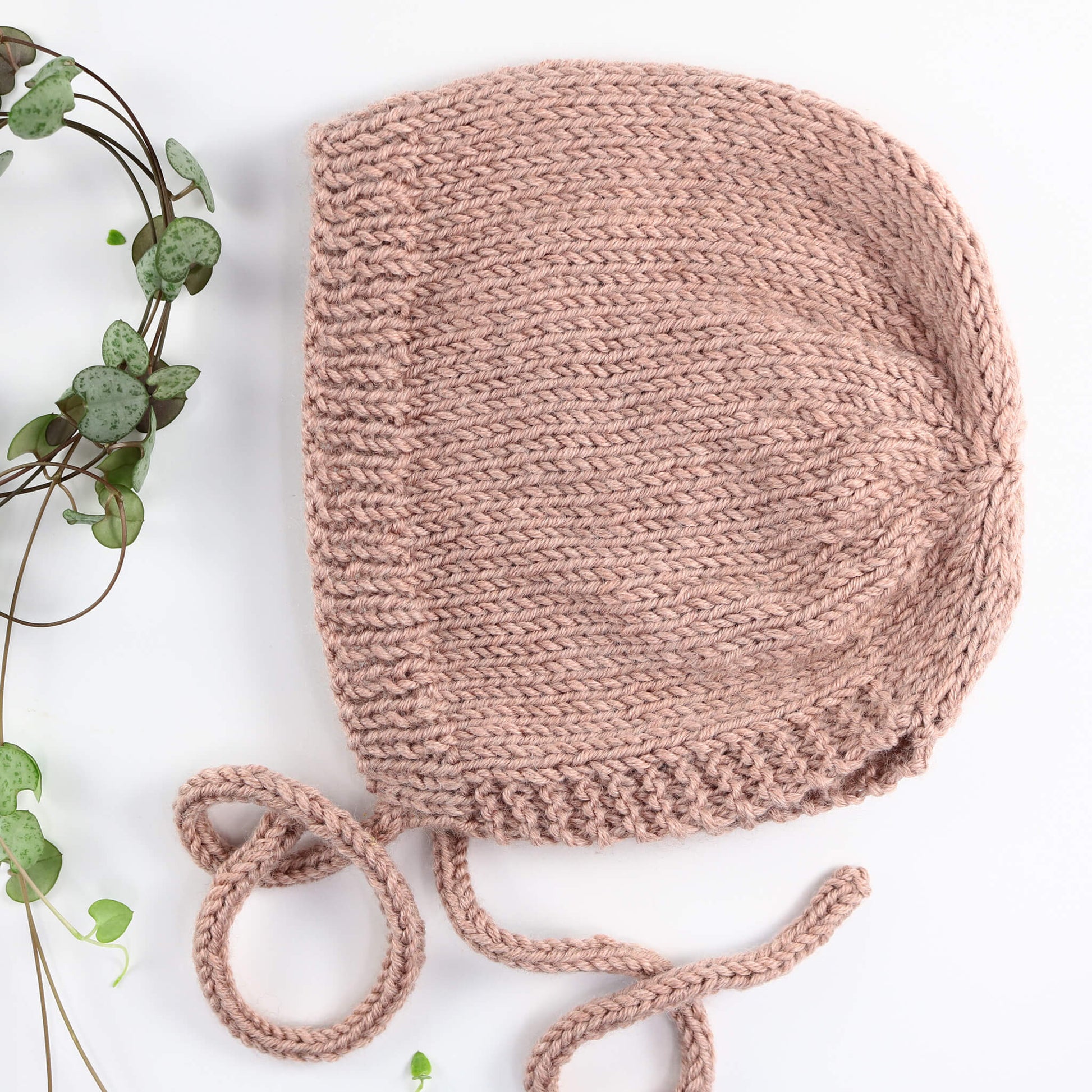 a bonnet knitting pattern for beginners knitted in pink yarn