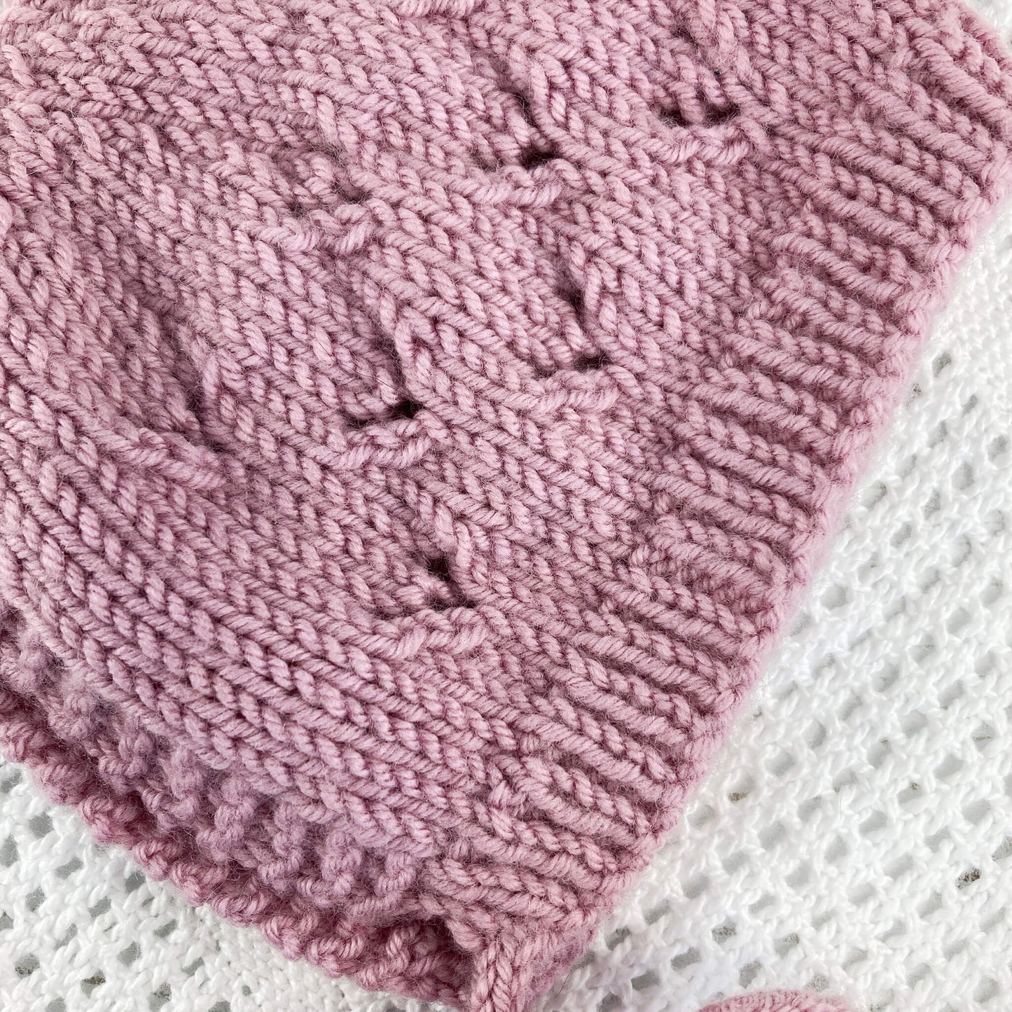 Photo shows the close up detail of the lace design on a baby bonnet knitting pattern