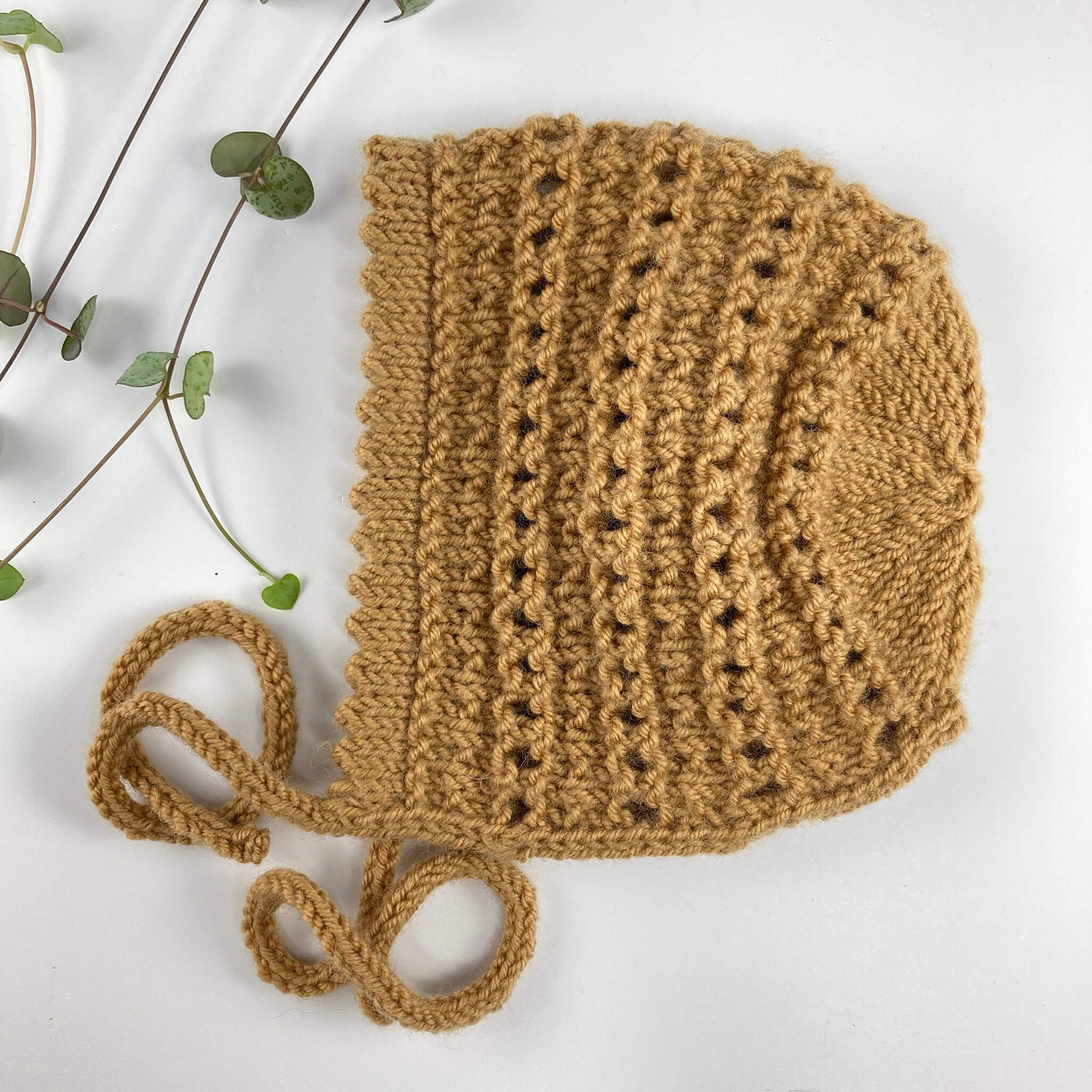 a bonnet knitting pattern with a picot edge shown knitted in mustard colour yarn