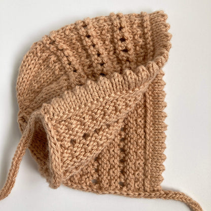 a bonnet pattern with lace knitting, shown open so you can see the inside