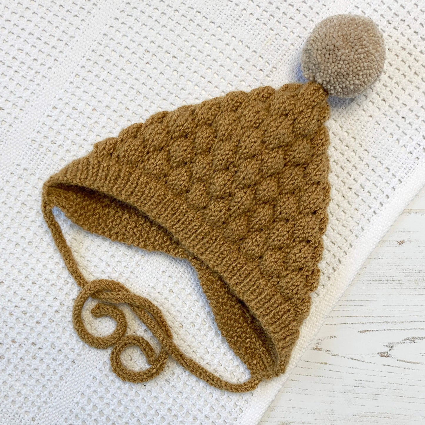 a bubble stitch baby hat pattern in mustard colour yarn