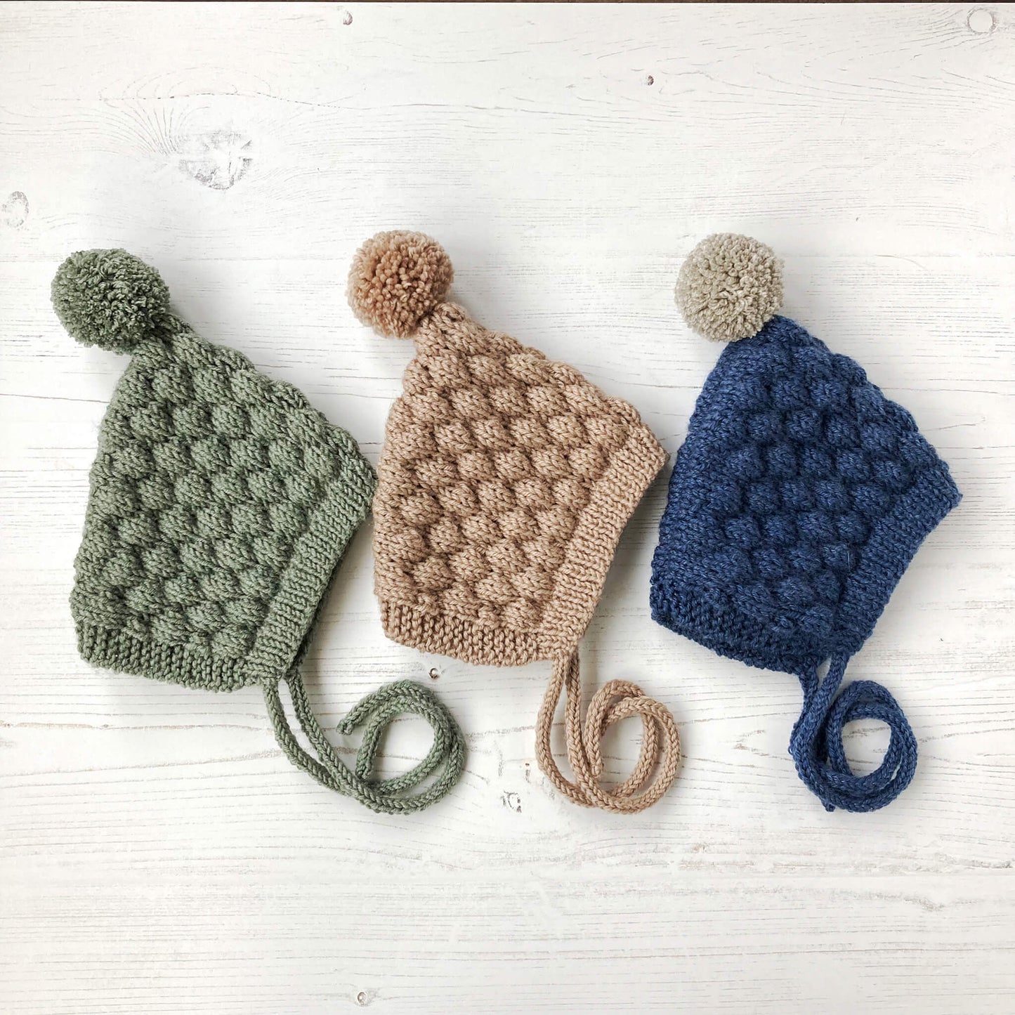 a bubble stitch pixie hat pattern shown in three colours