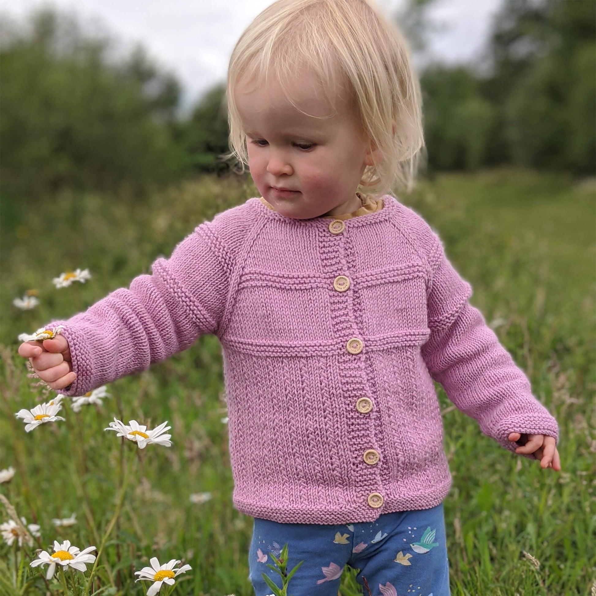 a toddler modelling a cardigan knitting pattern