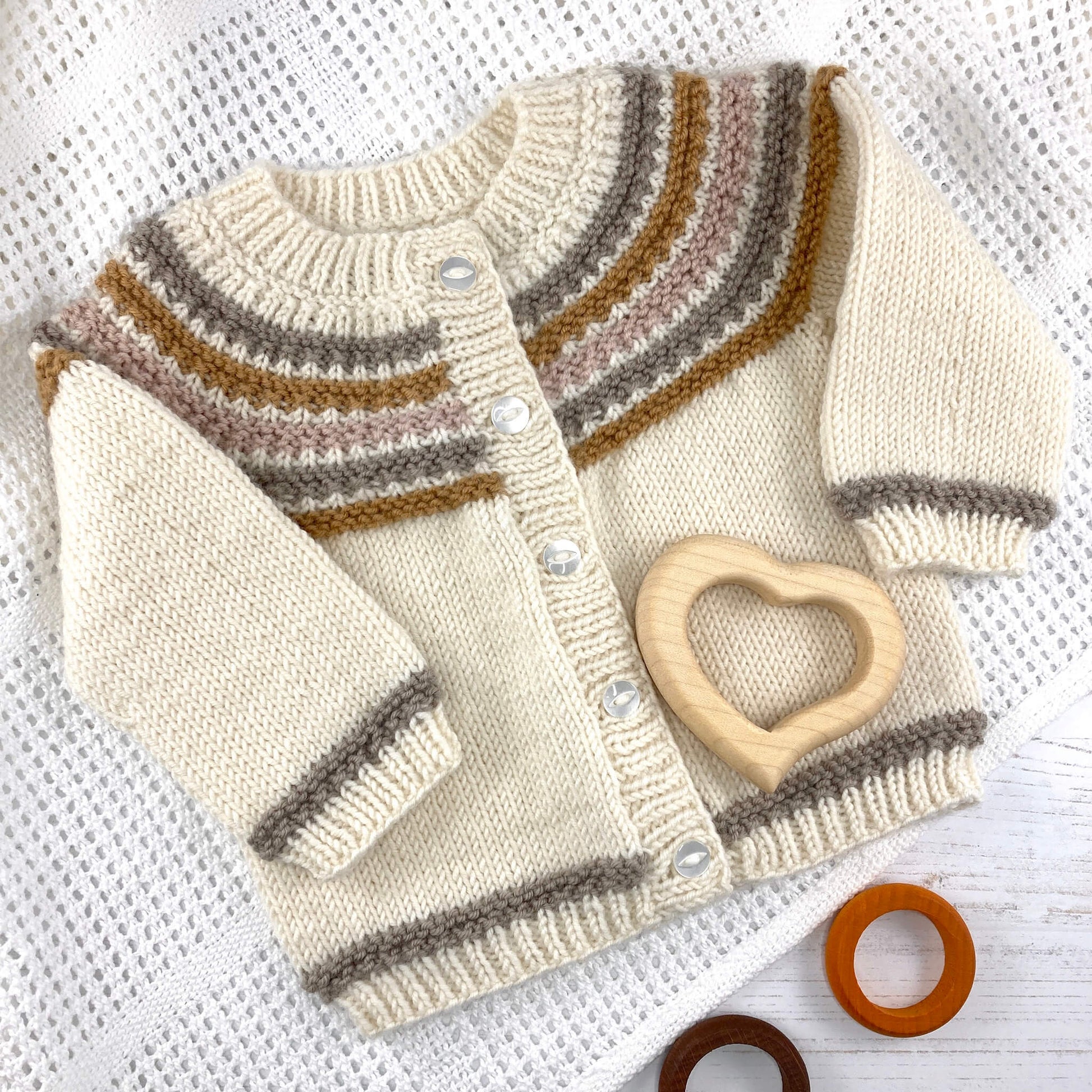 a circular yoke cardigan knitting pattern laying on a baby blanket