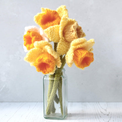 a daffodils knitting pattern. five knitted daffodils are shown in a small vase