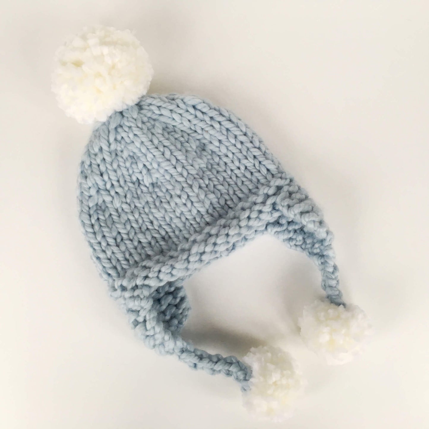 an easy hat knitting pattern. sample is shown in pale blue with white pompoms