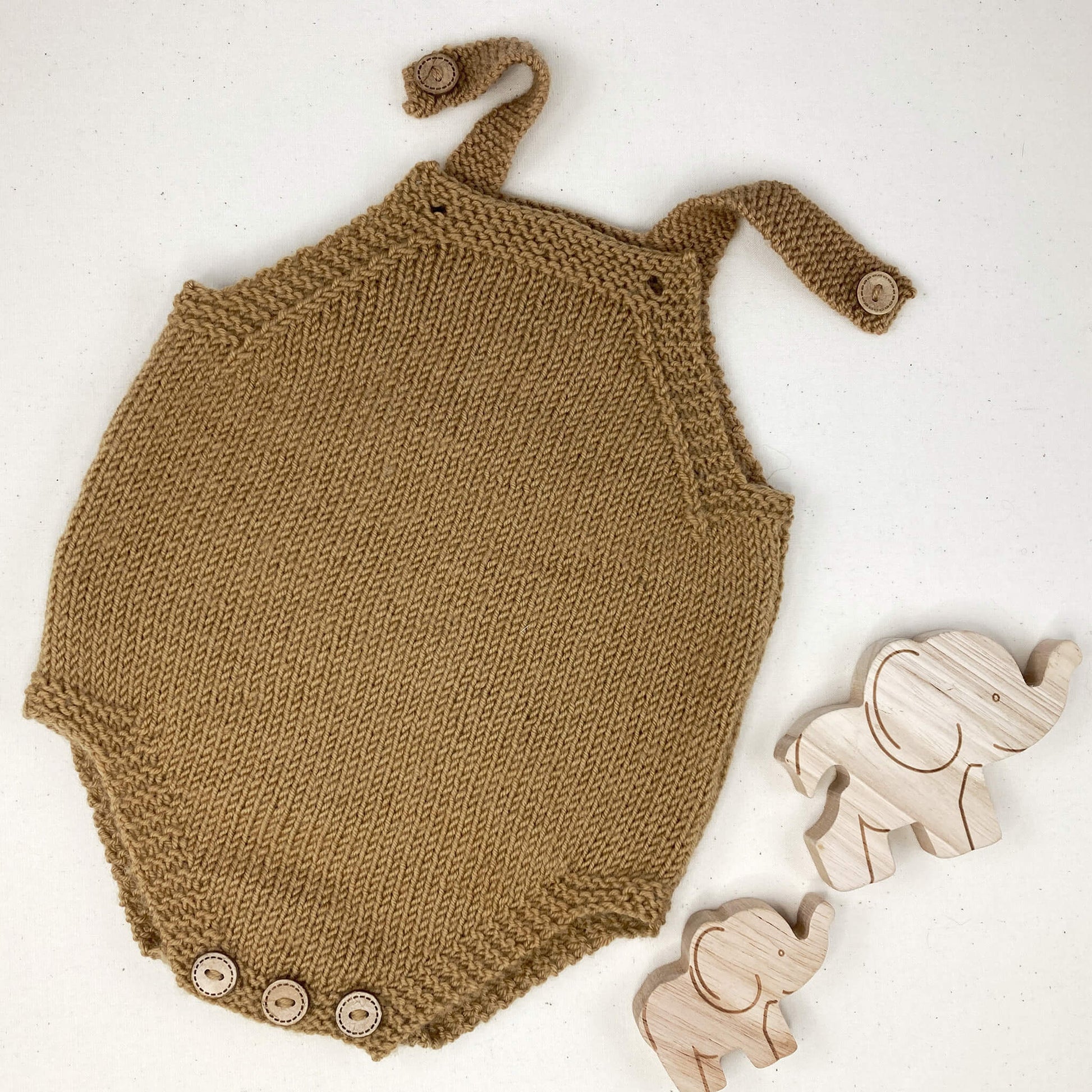 a flatlay showing an easy knitting pattern for a baby romper