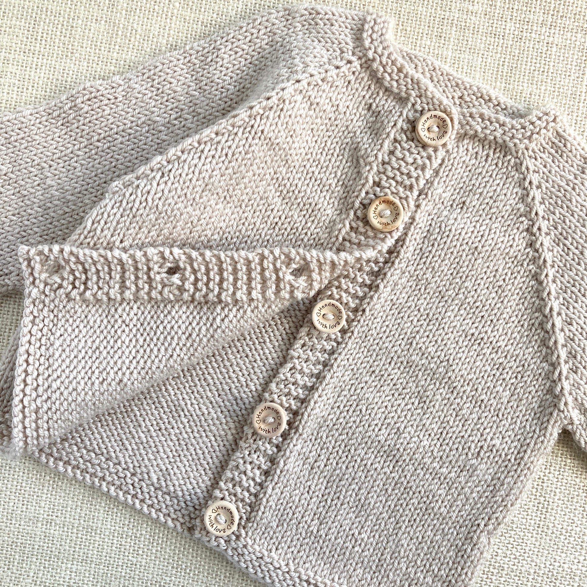 an easy knitting pattern for a baby cardigan shown with buttons open to display the inside of the cardigan