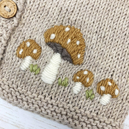 close up view of a toadstool embroidered baby cardigan knitting pattern