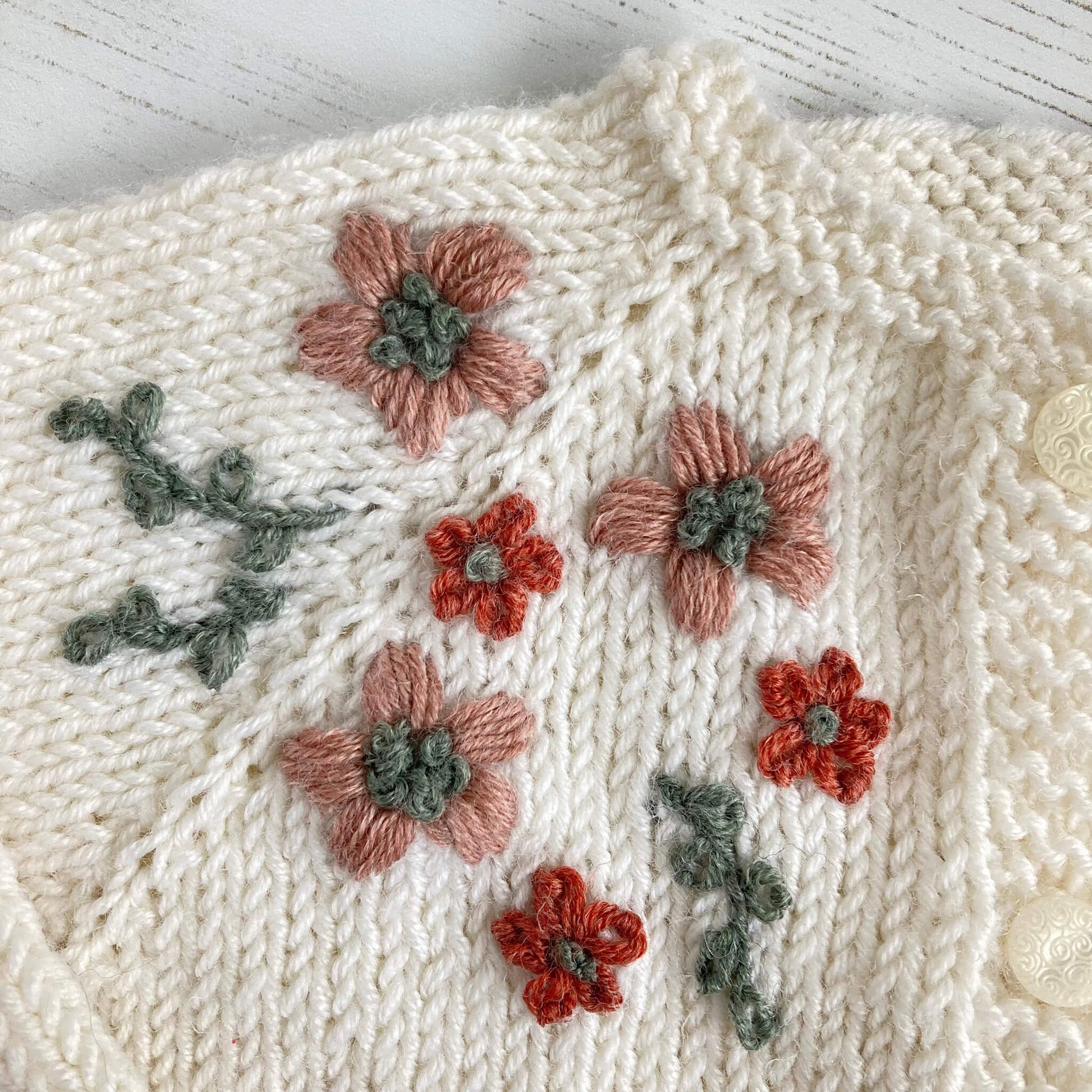 a close up of the flower embroidery on a baby cardigan knitting pattern