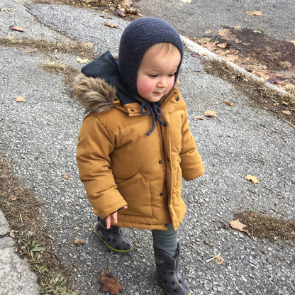 A toddler modelling a gender neutral bonnet for a baby bonnet knitting pattern