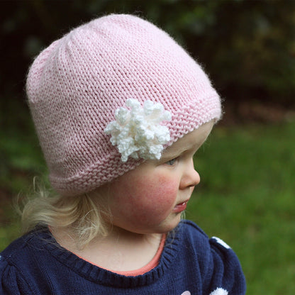 a kids hat knitting pattern modelled by a little girl 