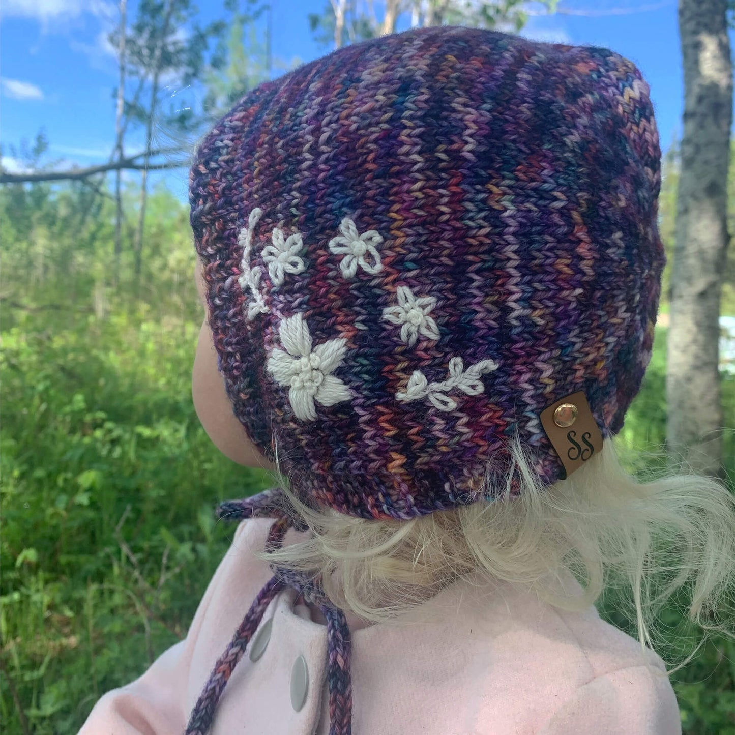 little girl modelling flower embroidered bonnet knititng pattern