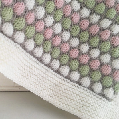 a knitting pattern for a baby blanket. photo shows a close up of the bubble stitch pattern