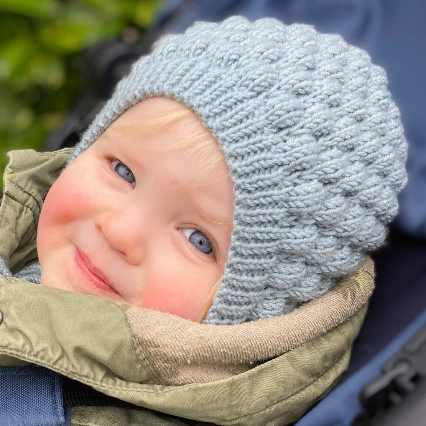 Baby wearing hat knitted using bubble stitch bonnet knitting pattern