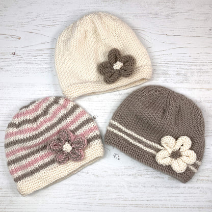 a knitting pattern for a baby hat with a flower. three variations and colours shown