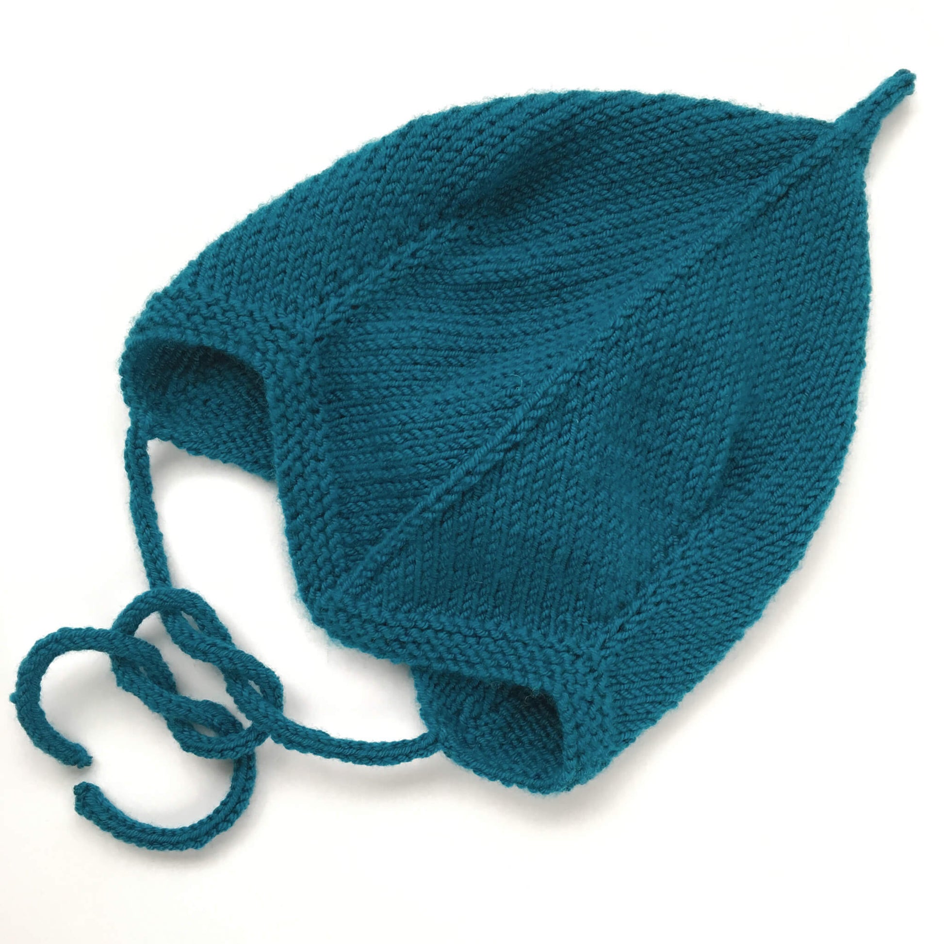 a knitting pattern for a baby pixie hat. sample shown is knit in petrol colour yarn