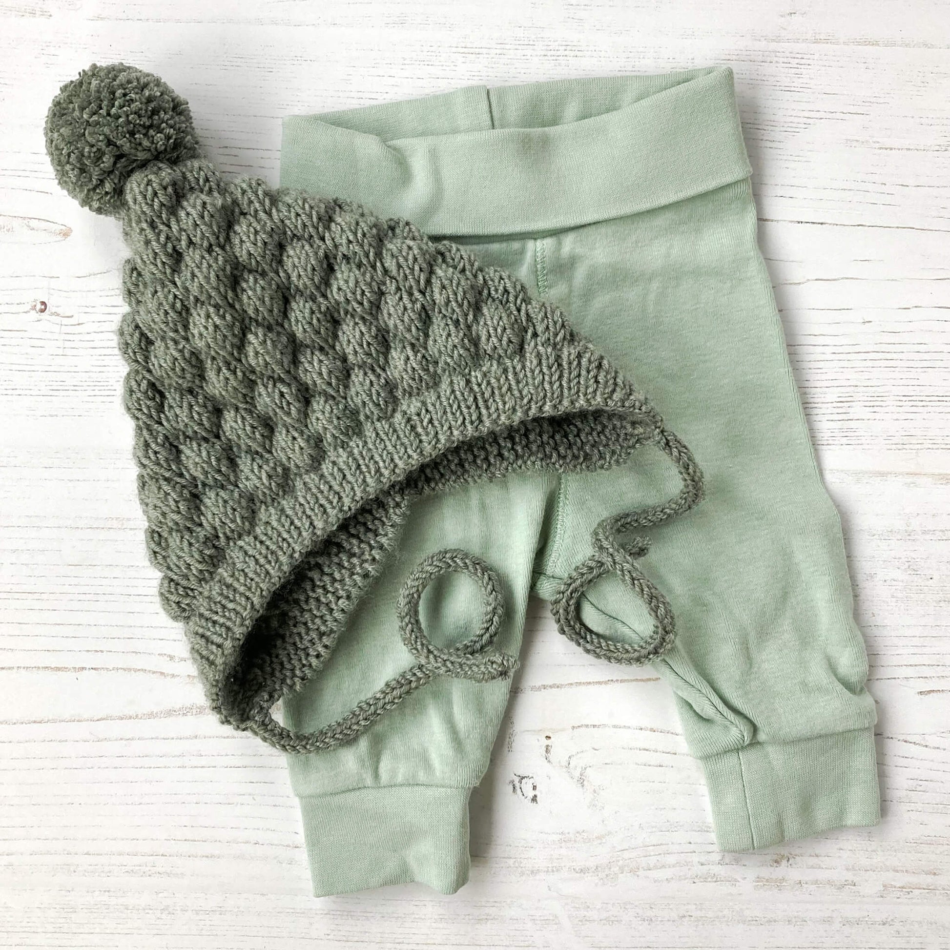 a knitting pattern for a baby pixie hat shown styled with baby pants