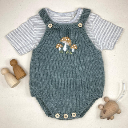 knitting pattern for a bay romper with embroidery on the front. Romper is shown with a striped T shirt underneath