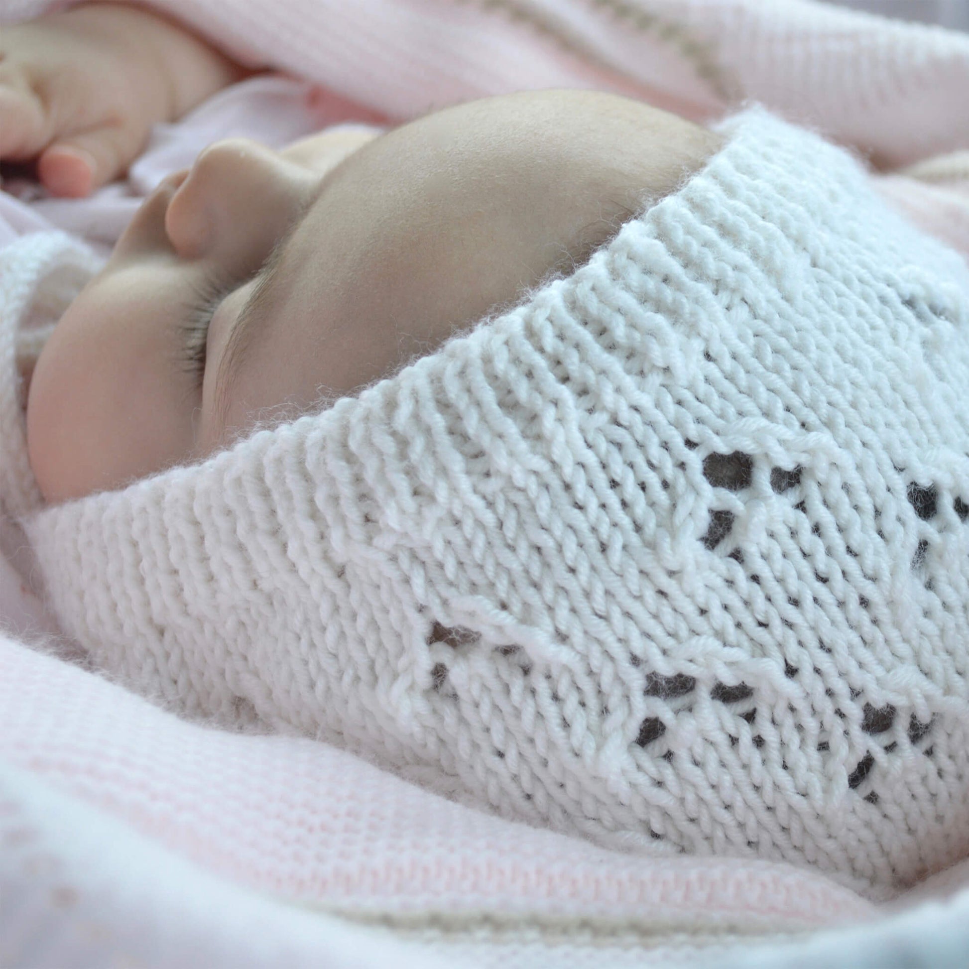 photo of a baby modelling a knitting pattern for a baby bonnet