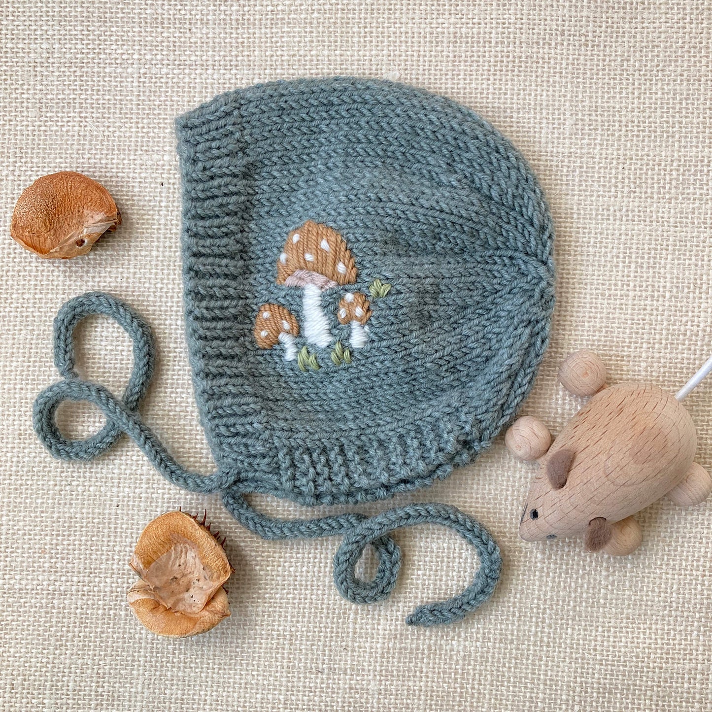 a knitting pattern for a baby bonnet with toadstool embroidery