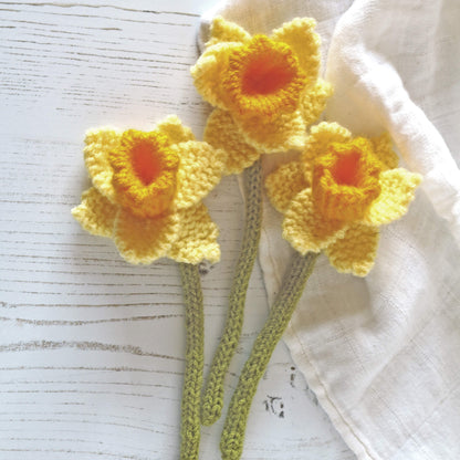 a knitting pattern for daffodils. three daffodils are shown laying on a white cloth