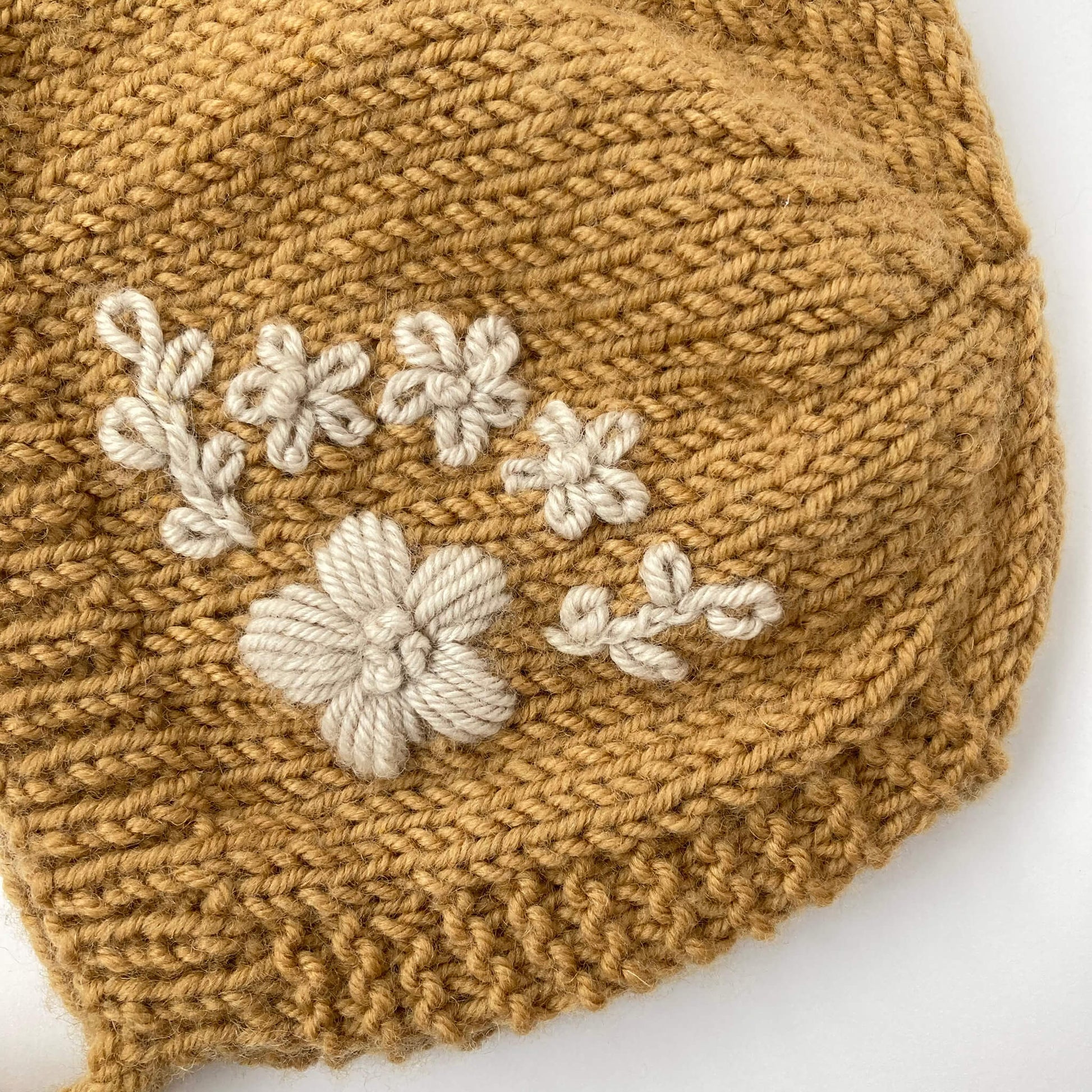 a close up of flower embroidery on baby bonnet knitting pattern