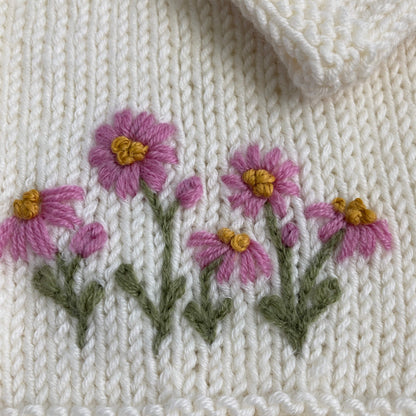 a close up of the daisy embroidery on a baby cardigan knitting pattern 