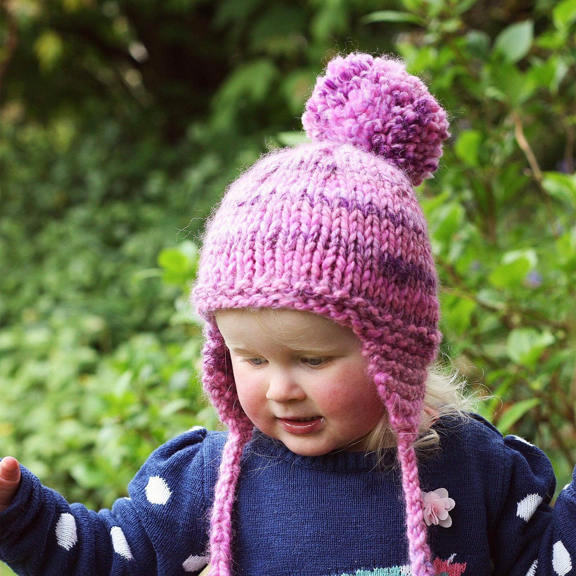 a knitting pattern for a kids hat modelled by a smiling girl