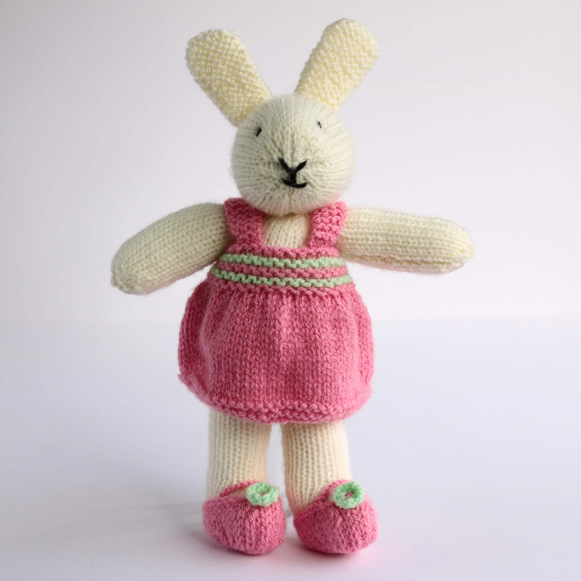 a knitting pattern for a rabbit doll. this rabbit is wearing a pink dress and pink shoes