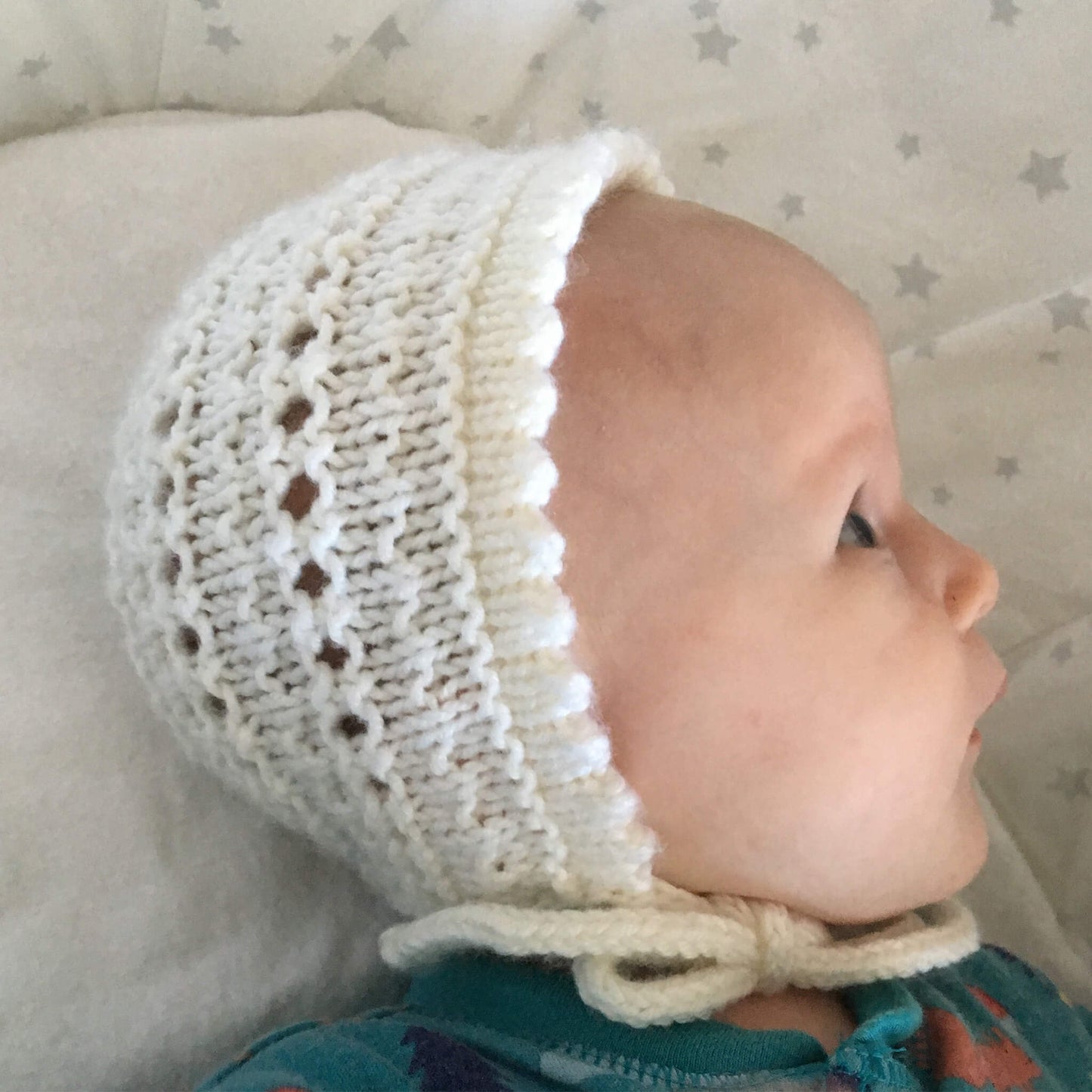 a baby modelling a picot edge bonnet knitting pattern