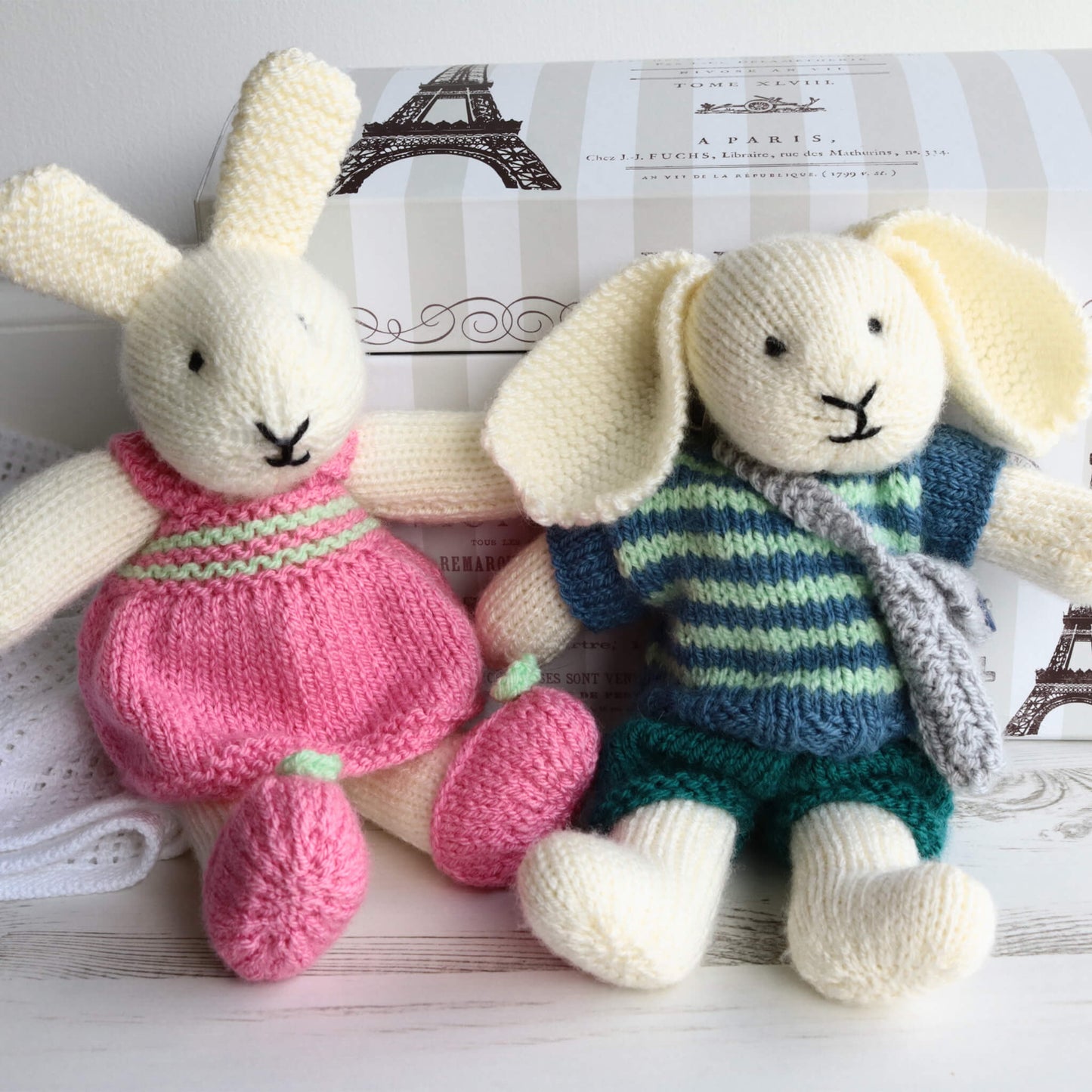 a rabbit soft toy knitting pattern. the rabbits shown are sitting against a toy chest