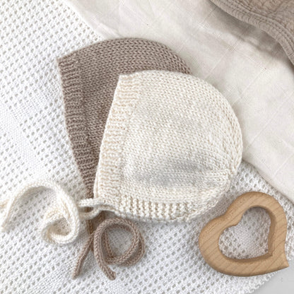 flatlay showing a simple knitting pattern for baby bonnet in neutral white and taupe