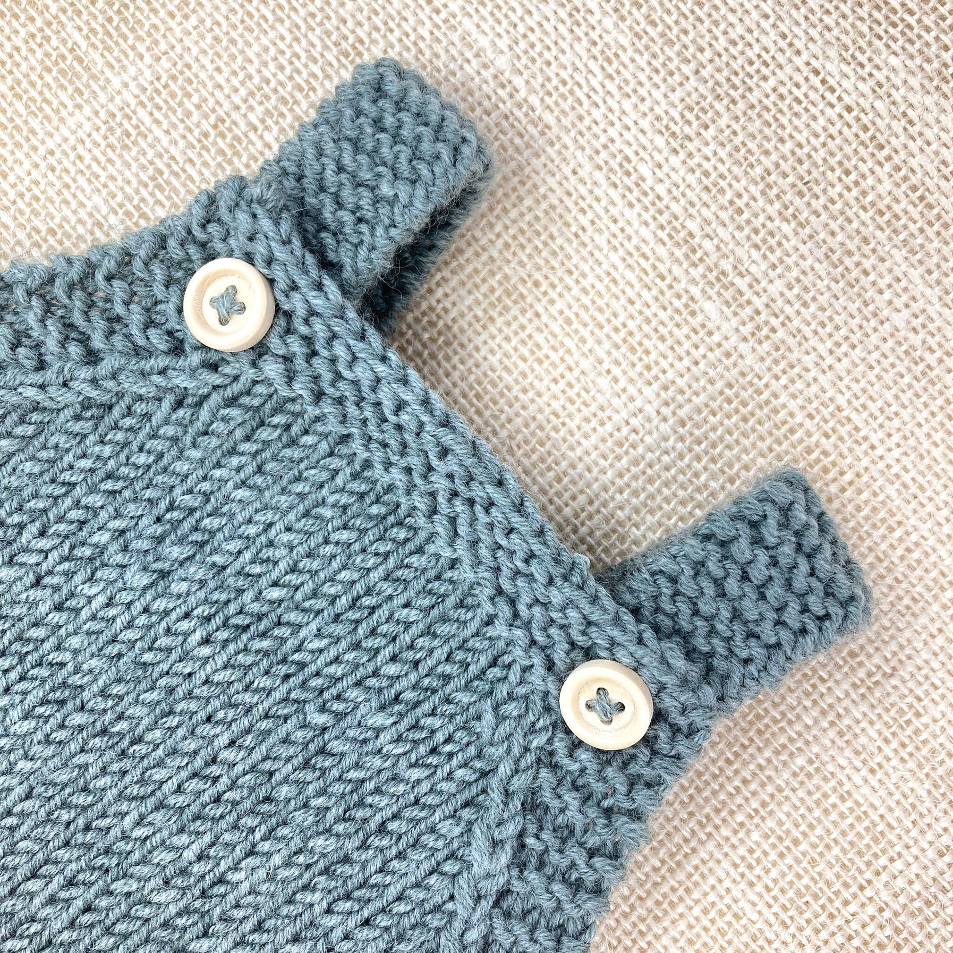 close up photo of the yoke and straps of a baby romper knitting pattern